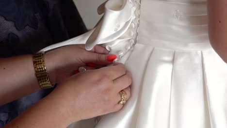 mother helping button up bride´s wedding dress close-up shot