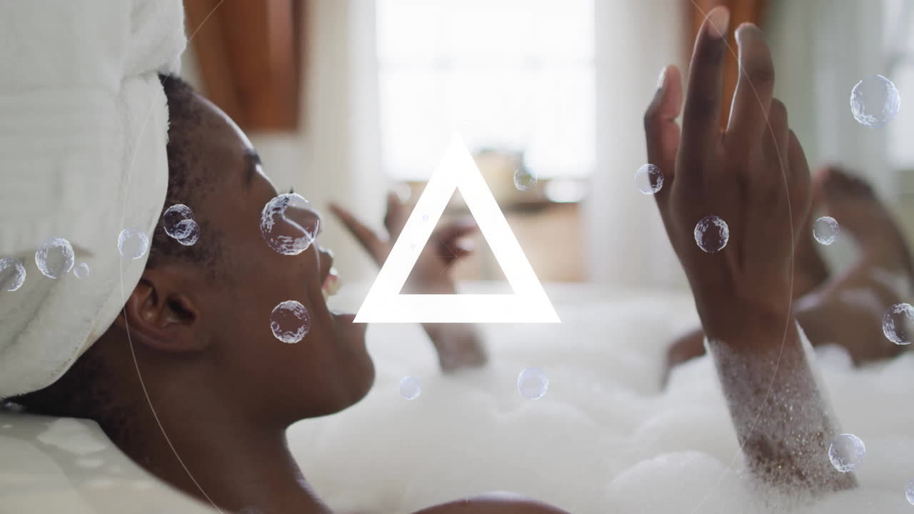 Woman reclining in bathtub using smartphone featuring animated bubbles and glowing beauty graphic