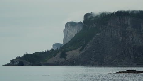 Wunderschöner-Nebliger-Morgen-Mit-Blick-Auf-Eine-Epische,-Mit-Bäumen-überzogene-Klippe-An-Der-Küste-Im-Forillon-National-Park,-Kanada,-Mit-Ruhigem-Golf-Von-St.-Lawrence-Waters-Im-Vordergrund