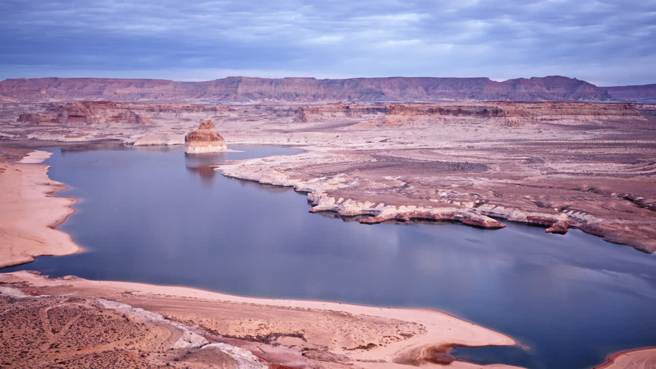 Drone shot gliding over a dramatic terrain, revealing Lake Powell and Glen Canyon in the distance.