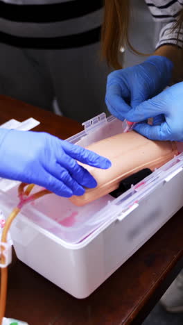 doctor in gloves making injection with a syringe for puncture. simulation medical training model. medical procedure concept, simulation medicine training. vertical video