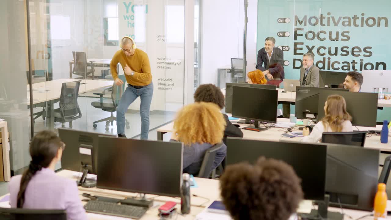 Coworker dancing happily on a corridor in front of colleagues