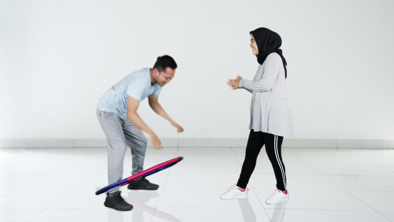 웃긴 젊은 남자가 라 후프로 운동하고 있습니다.