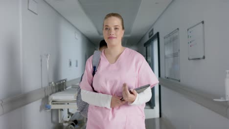 caucasian female doctor holding tablet and walking in corridor, slow motion