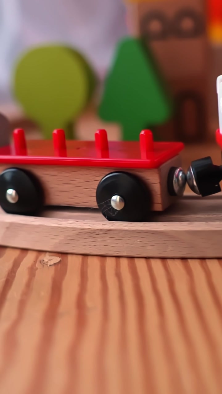 Vertical close-up of a toy train with glowing headlights rolling along a wooden track indoors, perfect kids playtime and model railway b-roll for family lifestyle scenes.