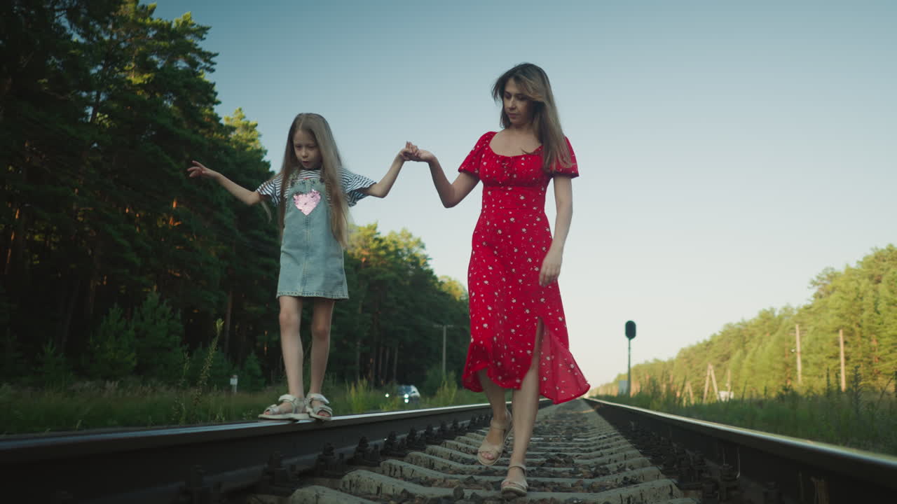 young boy in casual outfit walking alone on rail track surrounded by overgrown rural landscape, viewed from behind with converging railway lines creating deep perspective
