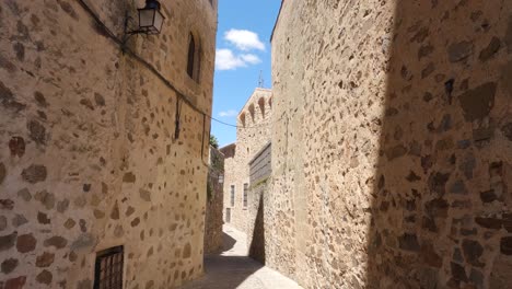 tilt down shot of stone walls in empty street in caceres old town, spain