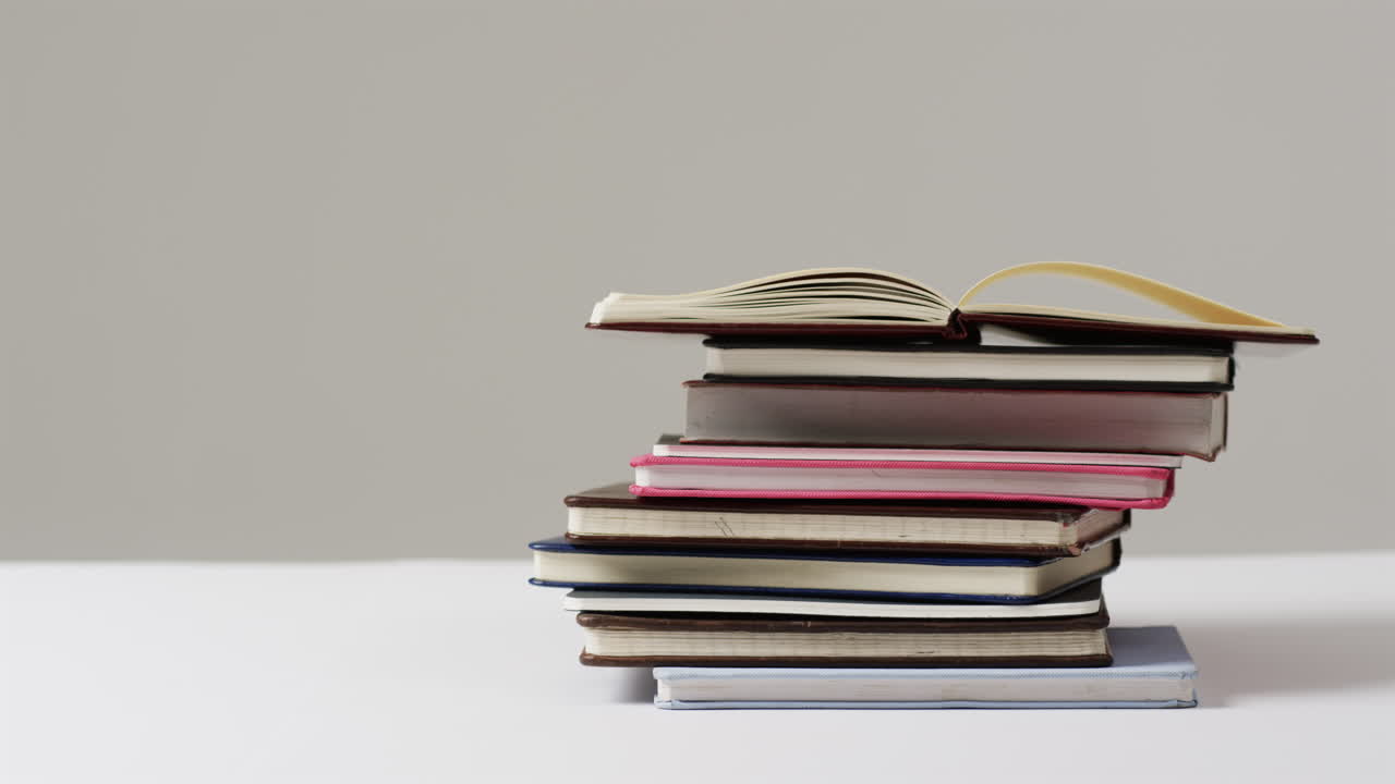 A stack of various books sits against a plain background, with copy space