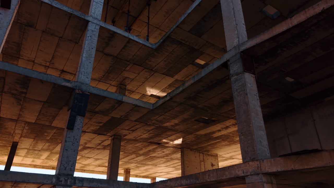 Descending along the empty floors of the construction. Abandoned unfinished multi-storied building from low angle view