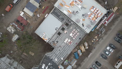 top down aerial of construction worker working under large construction site - drone lifting up and spinning