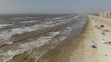 Elevated-stationary-shot-looking-down-at-the-beach-at-the-waves-and-people-swimming