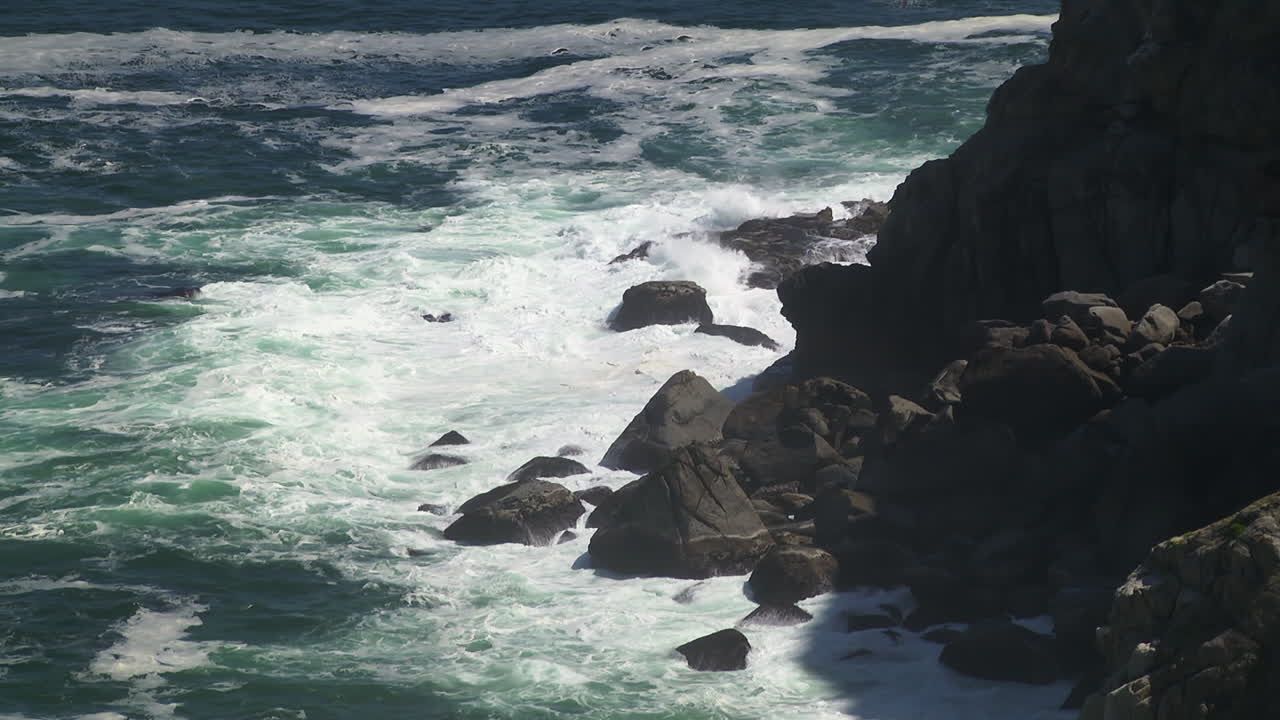 Onde dell'oceano che si infrangono contro le rocce a Capo Agulhas in Sudafrica. Rallentatore, inquadratura fissa.