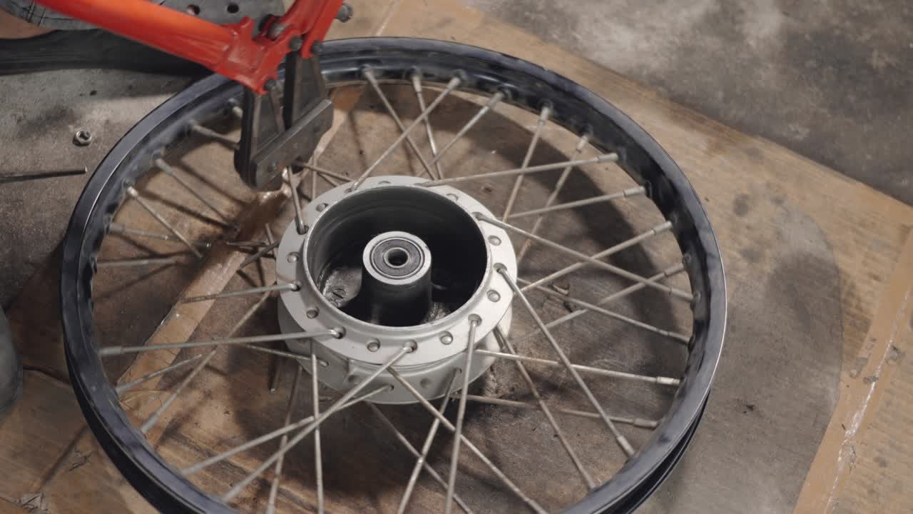 hombre mecánico de motocicleta usando pinzas de hierro. cortar los rayos de la alineación de las ruedas