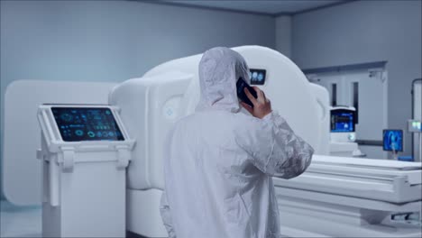 back view of asian male scientist talking on smartphone while standing with mri machine in the hospital