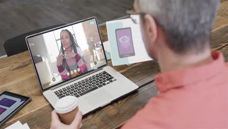 hombre de negocios caucásico en una llamada de video portátil con una colega afroamericana en la pantalla
