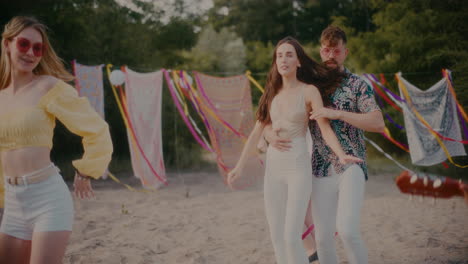 una pareja joven bailando bachata mientras está rodeada de amigos en la playa
