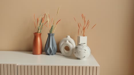 modern vases with dried flowers on a white table