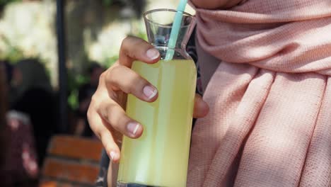 woman in pink scarf drinking lemonade outdoors