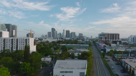 forwards fly above town development, high rise apartment buildings in background. railway track leading through city. miami, usa