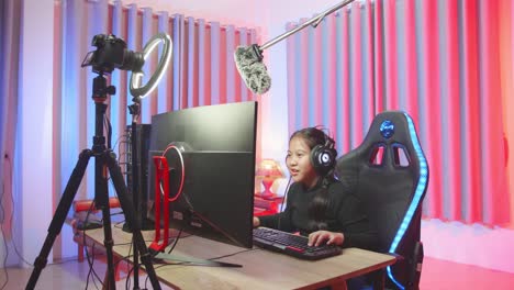 young gamer girl with headphones plays video game on a computer