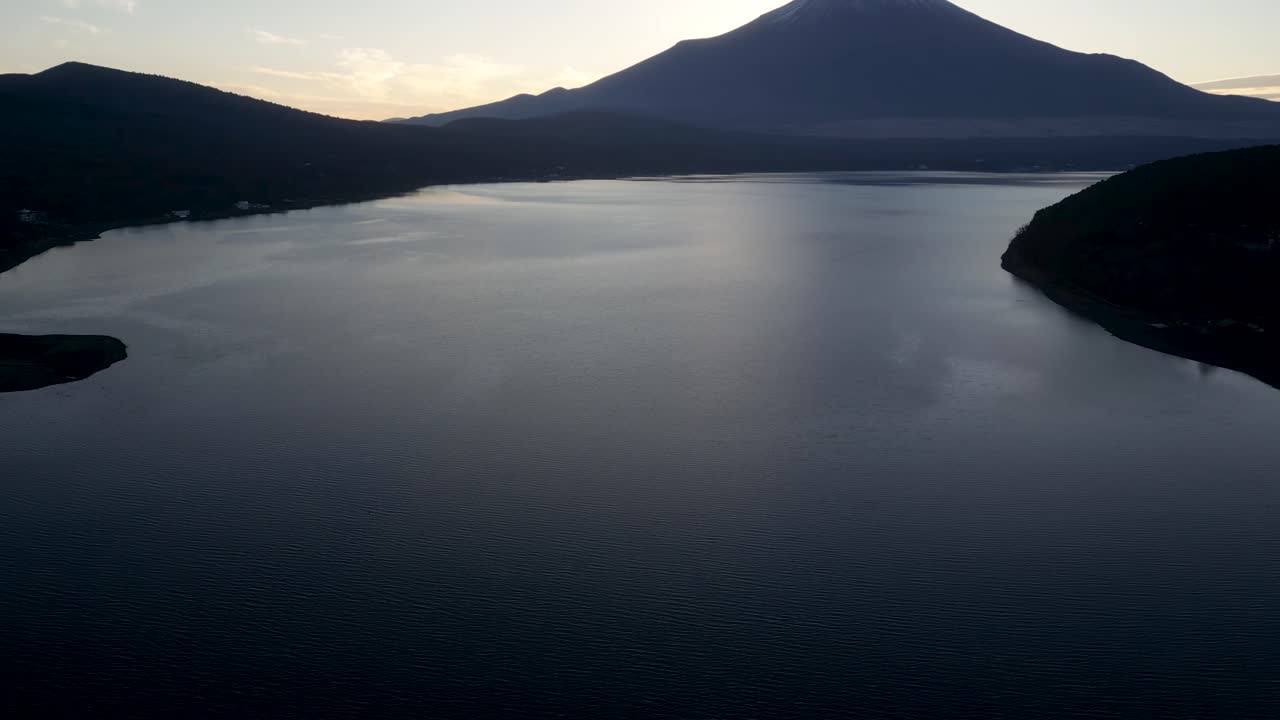 Perfect cinematic drone reveal shot of Mt. Fuji over lake at sunset