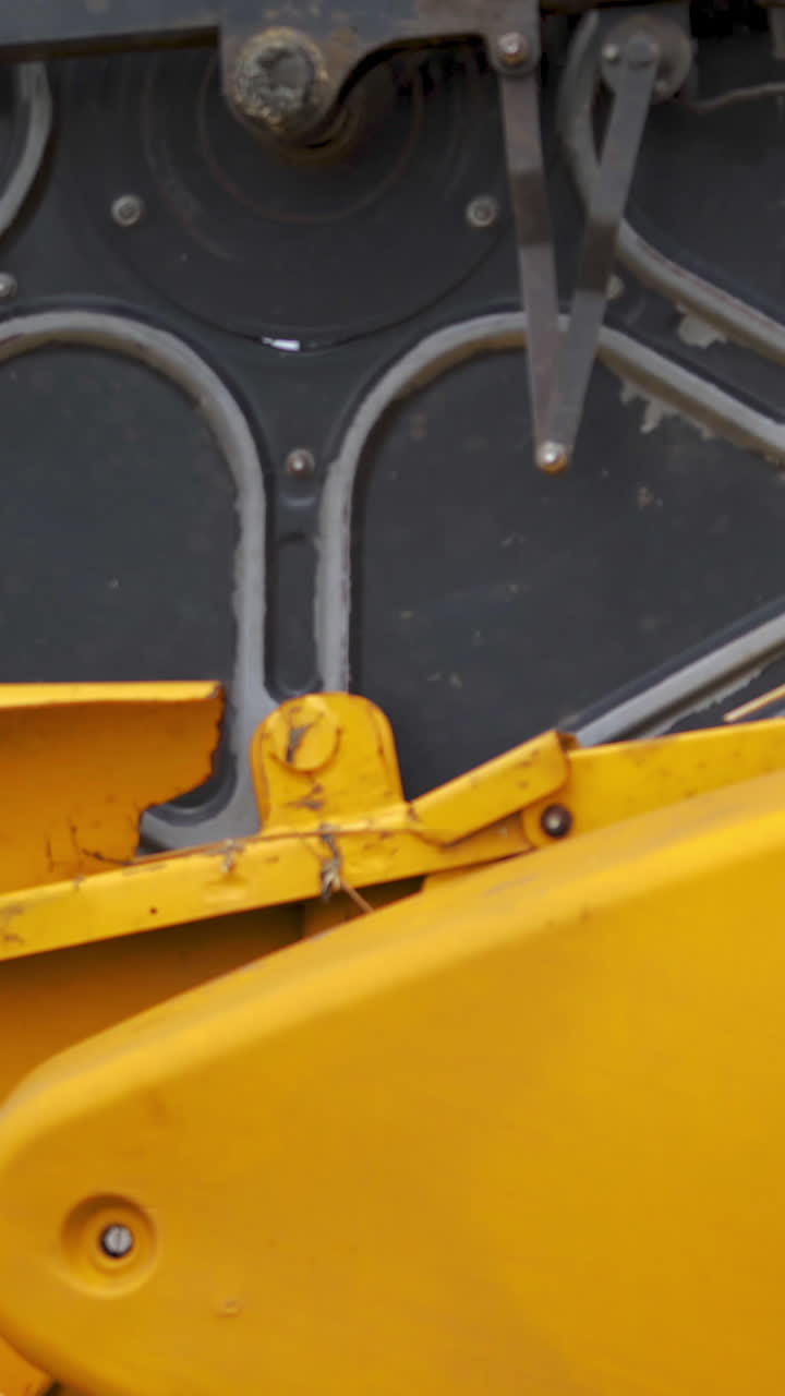 Harvester mower mechanism on field. Combine harvester moves on field. Agricultural harvesting works. Large harvester during seasonal works. Agricultural business. Vertical video