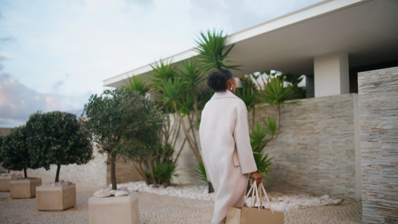 Donna che cammina in una casa moderna di sera. Elegante donna afroamericana che entra in casa.