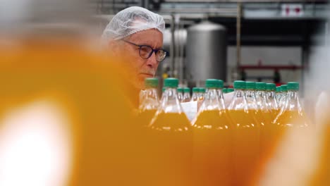 Worker-examining-a-bottle-in-factory