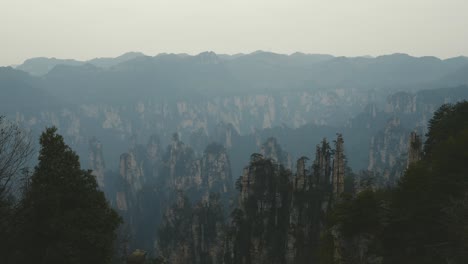 an extensive view over zhangjiajie’s renowned rock pillars, set against layers of misty mountains fading into the evening light, highlighting the surreal beauty of this chinese landmark