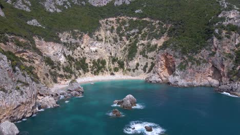 aerial, approaching pebble cliff beach with no people on corfu, greece, slow-motion