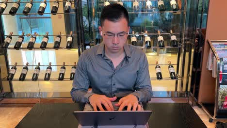 hombre asiático del milenio asintiendo con la cabeza a la música mientras trabaja en una computadora portátil dentro de una casa de lujo