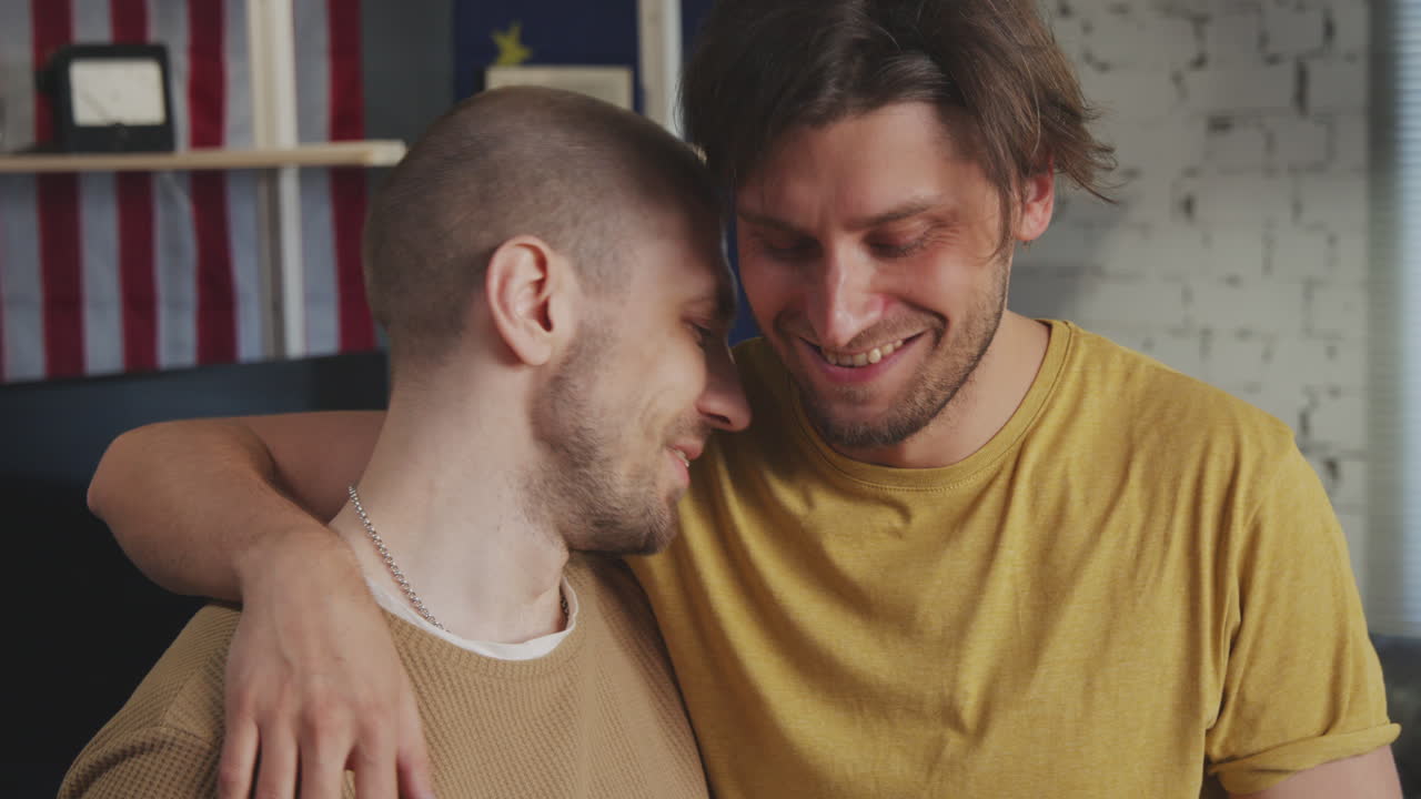 Man Drinking Coffee and Being Hugged by Male Partner