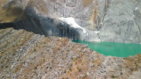 a dynamic aerial parallax shot reveals a dramatic and steep mountain ridge separating two vibrant turquoise glacial lakes on the remote huayhuash trek in the peruvian andes