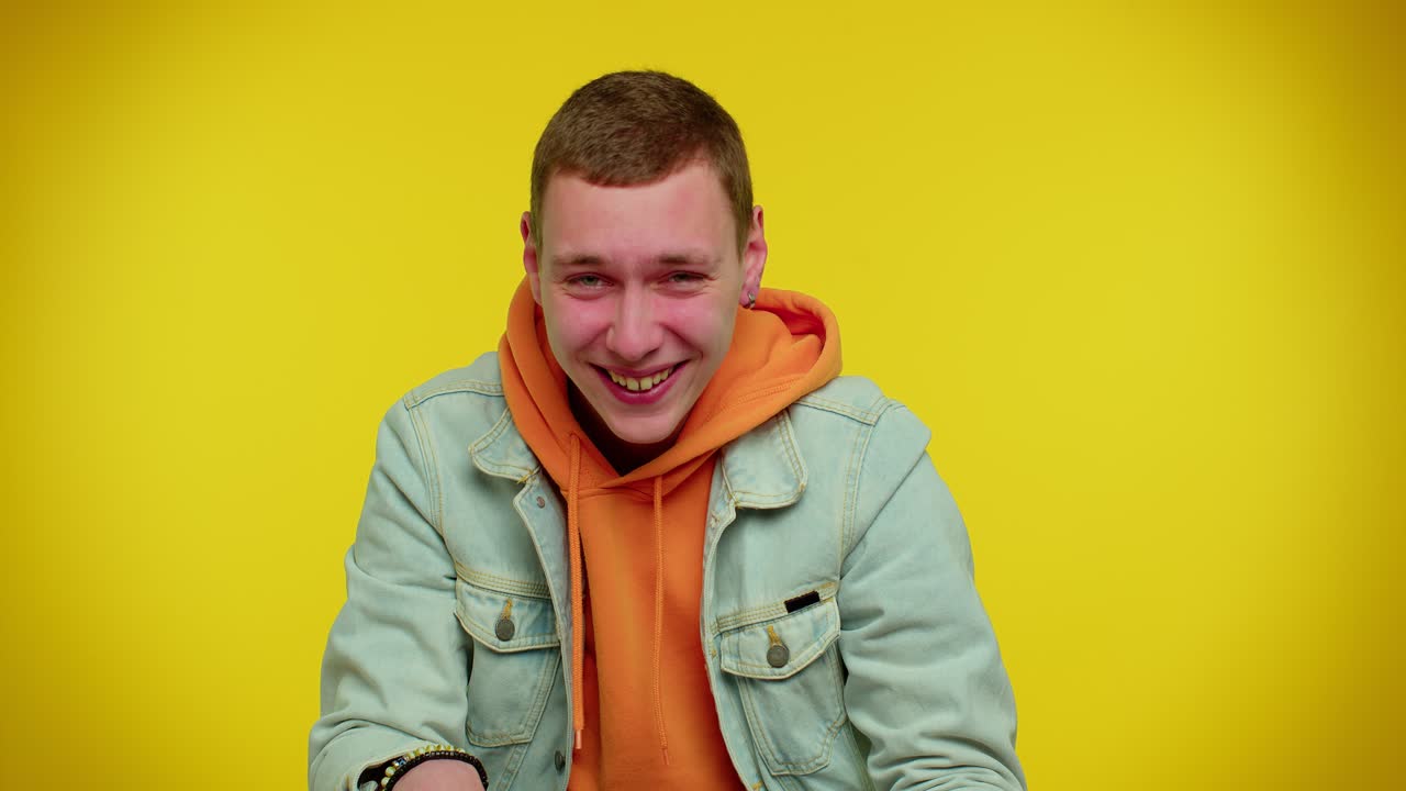 Young man laughing out loud after hearing ridiculous anecdote, funny joke, feeling carefree amused