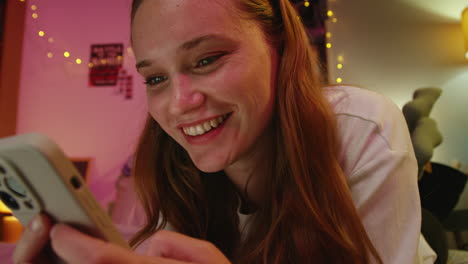 smiling woman looking at phone in bed