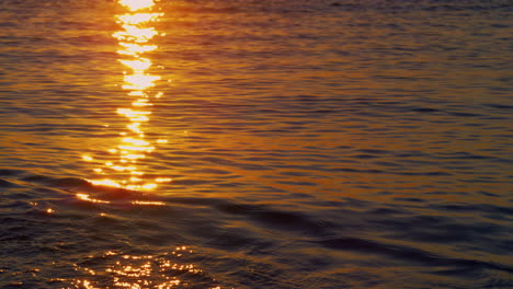 Blick-Auf-Das-Meerwasser,-Das-Die-Sonnenstrahlen-An-Der-Küste-Reflektiert.-Ruhiger-Sonnenaufgang-Am-Strand.