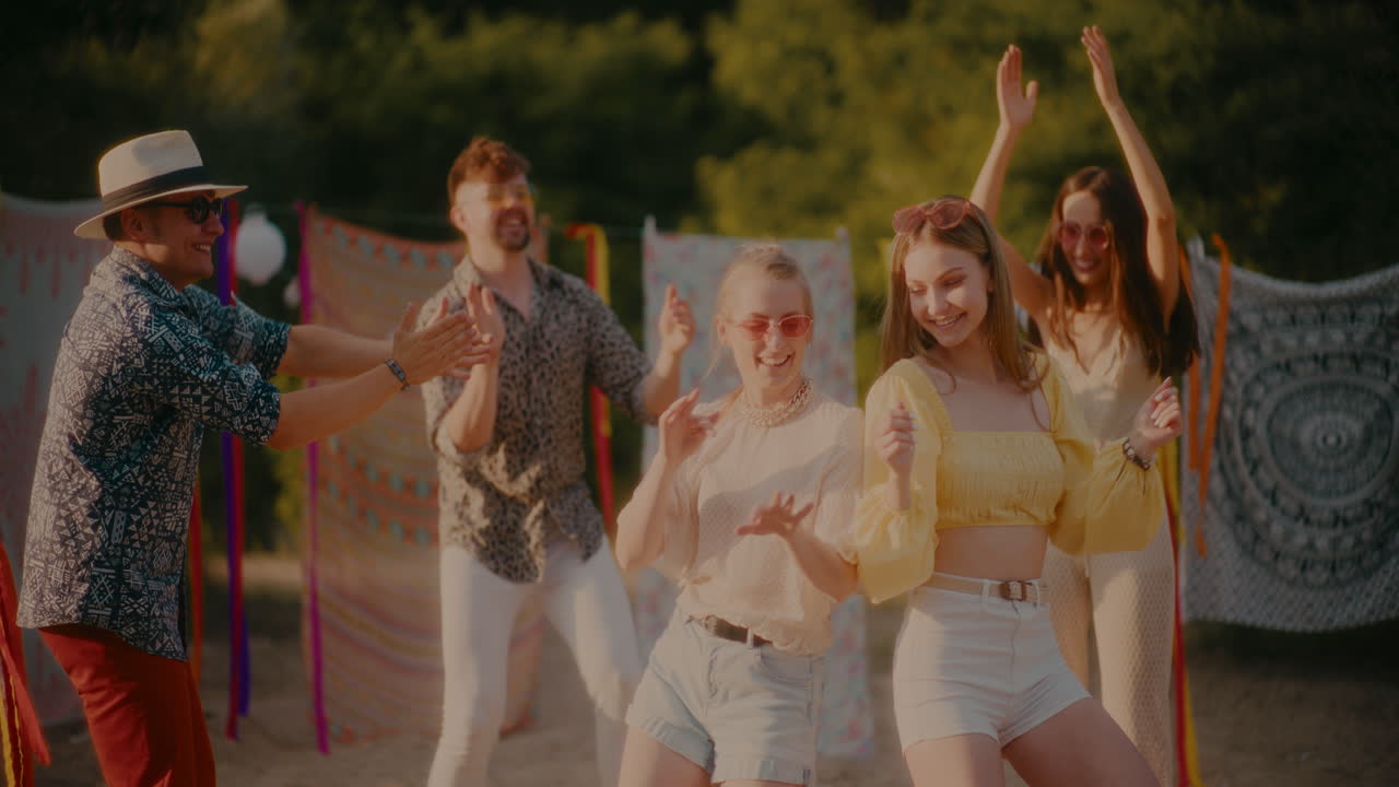 Happy young friends grooving together at beach during sunset