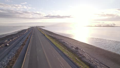 vancouver scenic aerial sunset of main highway leading to tsawwassen ferry terminal, cars driving fast along the main road over the ocean water reaching bc ferries