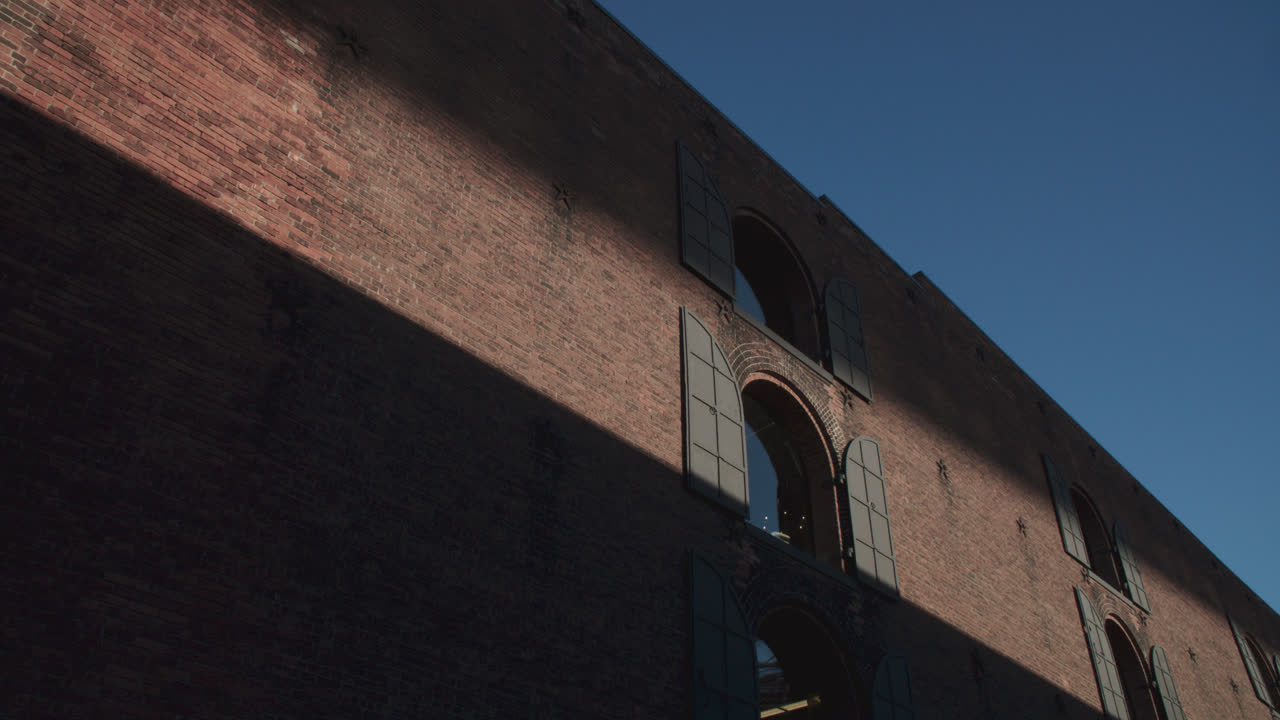 Shadows and a beam of light cast on a brick wall in Brooklyn