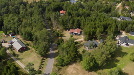 Road-winding-between-trees-and-low-houses-in-village.-High-angle-footage-of-car-going-on-road.-Denmark