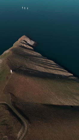 aerial view of a coastal cliff and lake with sailboats