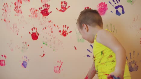 Happy-mother-and-her-cute-boy-having-fun-together-leaving-their-colorful-handprints-on-the-wall.-Young-happy-family.-Mother-and-child-concept