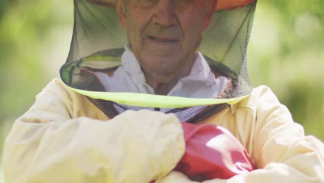 portrait of smiling caucasian male beekeeper in protective clothing with arms crossed