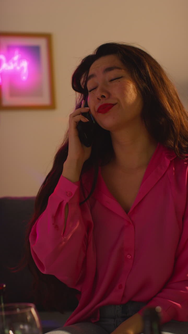 Vertical Video Of Woman Sitting On Sofa After Drinking Alcohol At House Party Suffering With Hangover Answering Mobile Phone