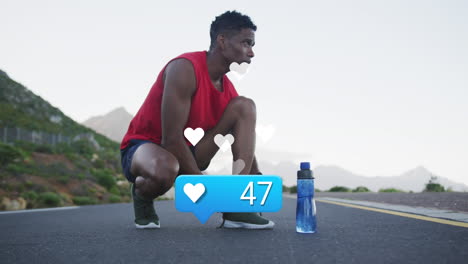 animation of heart icon and number over african american male athlete tying shoelace on street