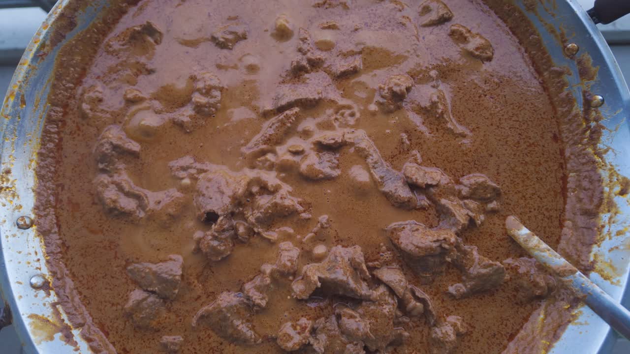 Authentic Indonesian beef rendang cooking in a large wok, with rich, aromatic sauce bubbling to perfection. Slow-cooked for deep flavor and tender texture. Perfect for food lovers