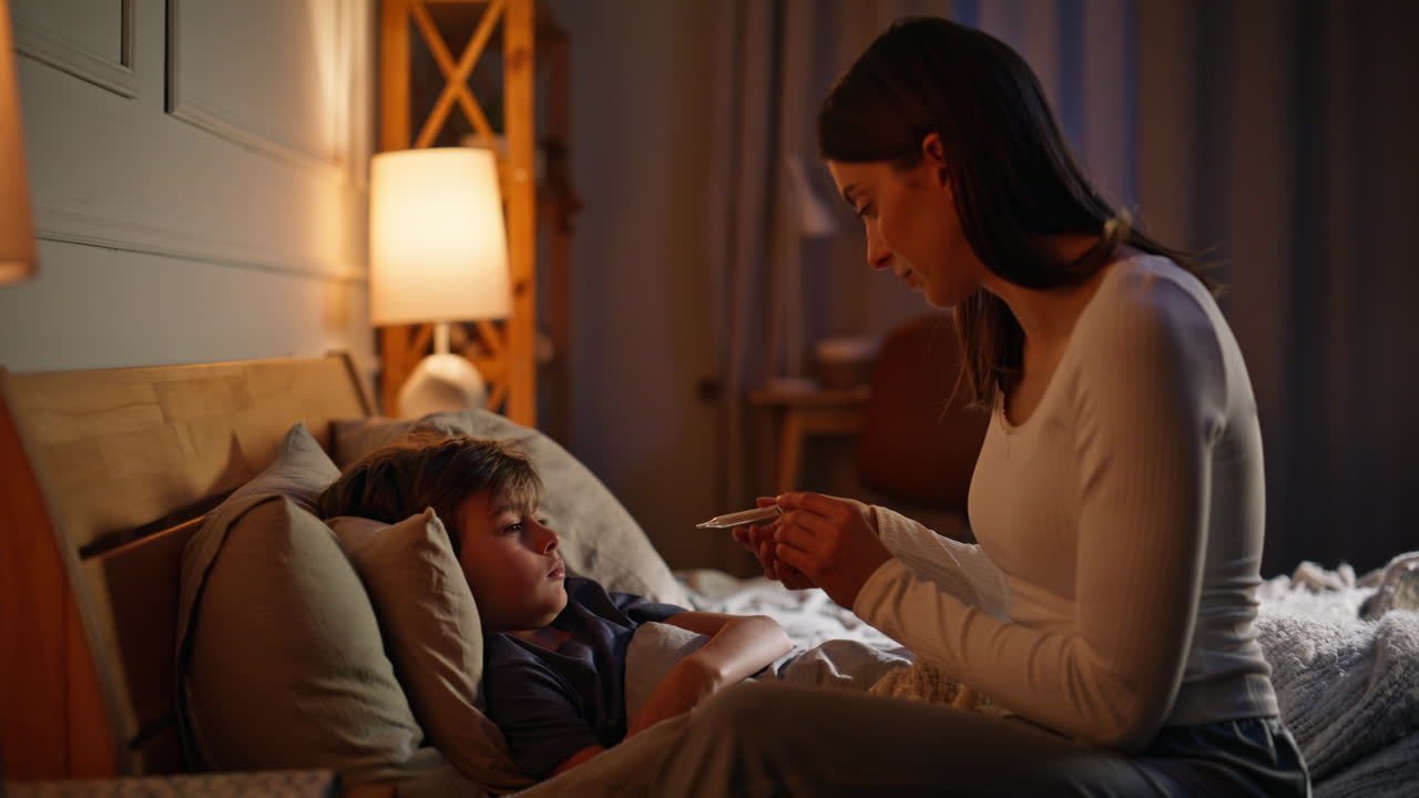 Mom worried son health touching forehead at bedtime closeup. Caring mother