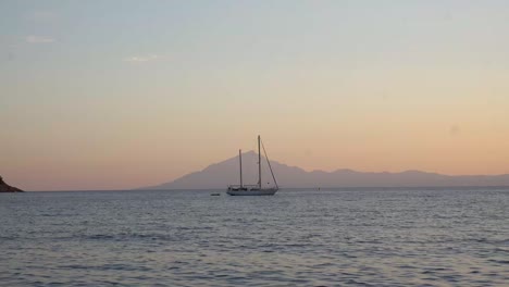 Barco-Aislado-En-La-Playa-Al-Atardecer-Con-Fondo-De-Montaña