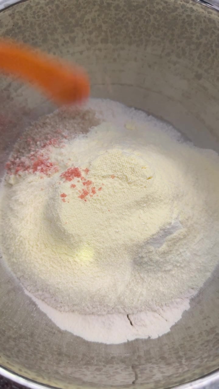 Aggiunta di sale rosa a farina e ingredienti in polvere in una ciotola per mescolare