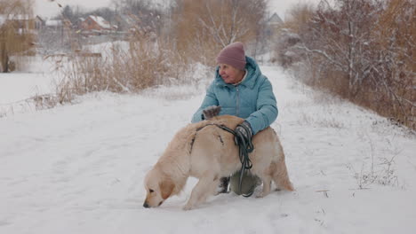 woman with golden retriever in snowy park